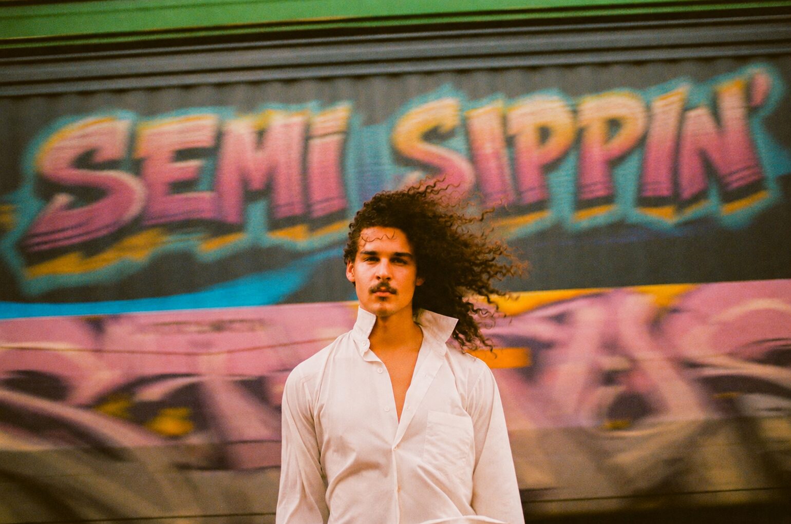 Semi Sippin' tagged across a freight car, a man in a white shirt in front of it